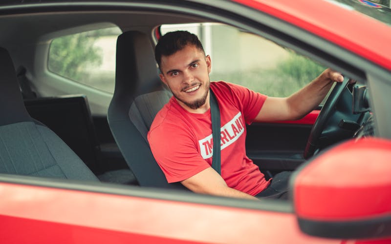 Smiling driver wearing a seatbelt behind the wheel